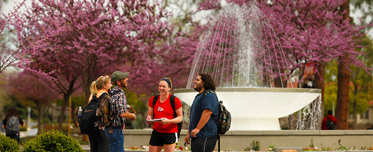 Four Fresno State students standing in front of the Memorial Fountain on campus