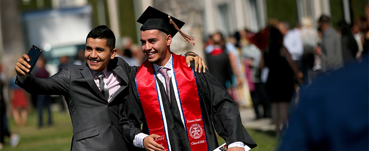 Family member taking a photo with a Fresno State graduate after Commencement